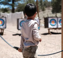 Young boy at Camp participating in Archery.